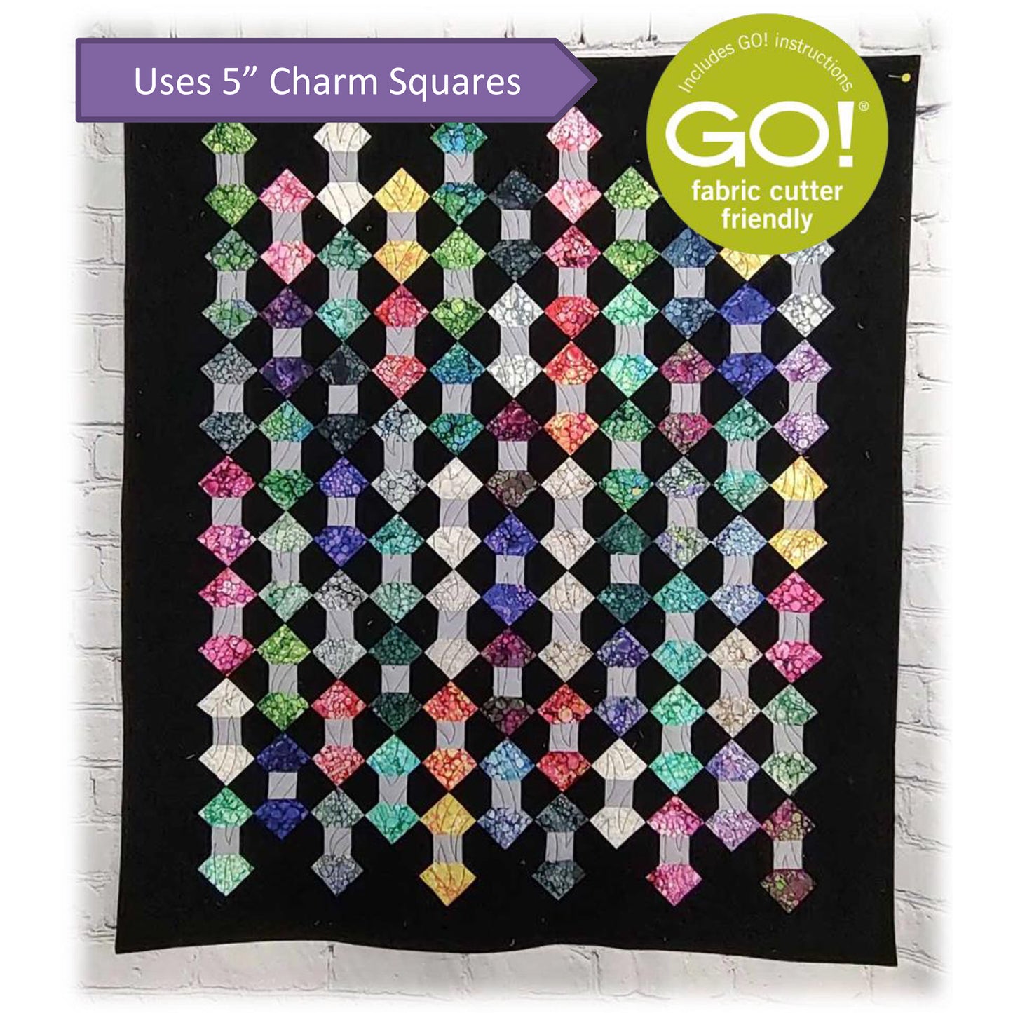 Colorful quilt is scrappy with rows and columns of two diamonds attached by a small strip of gray fabric.  Makes it look like bowties or could be skeins of yarn.