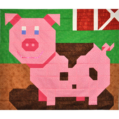 Adorable smiling pig quilt in a mud puddle with part of a barn in the background.