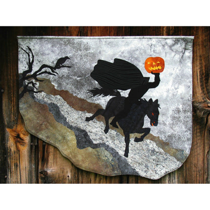 Headless horseman with jack-o-lantern wall hanging with eerie tree in background.