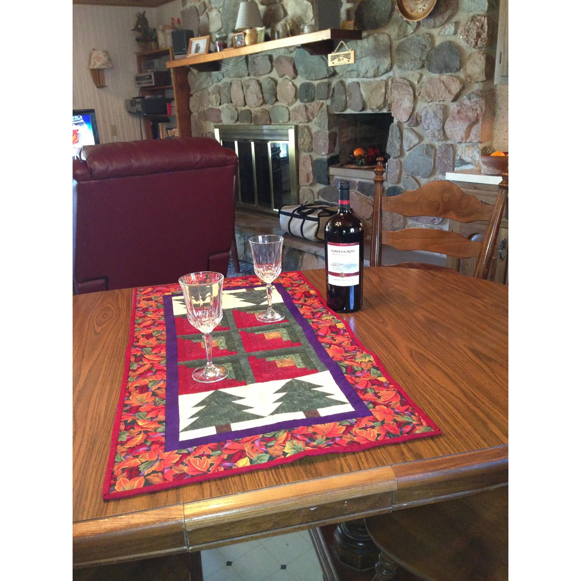 A rustic table set with a wine glass and a bottle of wine, perfect for cozy evenings by the fire at a lakeside cabin.