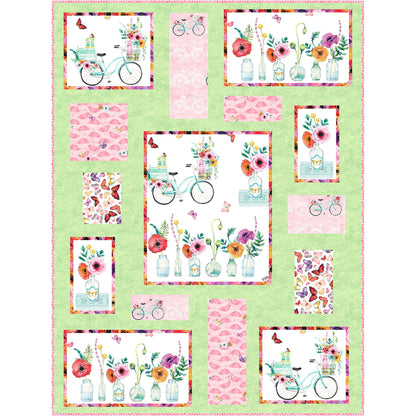 Colorful quilt with flowers and bicycles in pretty pinks and green with a green background.